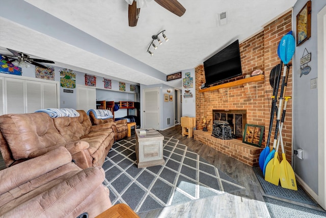 living room with a ceiling fan, wood finished floors, baseboards, and a textured ceiling