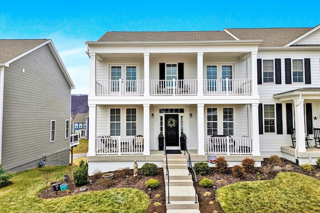 view of front facade with a porch, a shingled roof, and a balcony