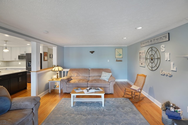 living room with light wood-type flooring, a textured ceiling, and ornamental molding