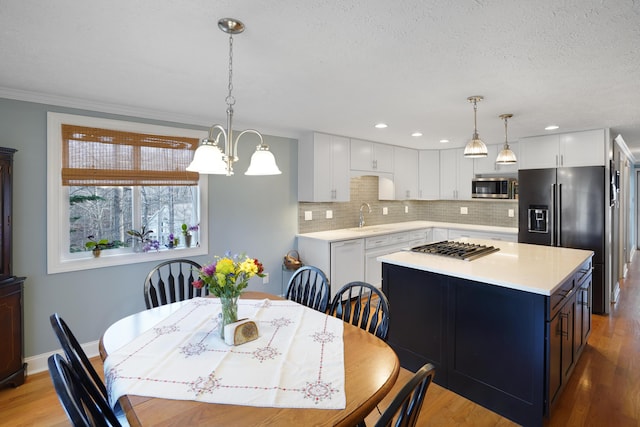 dining space with recessed lighting, light wood-style flooring, a textured ceiling, and baseboards