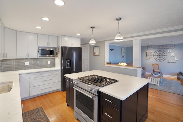 kitchen with tasteful backsplash, premium appliances, light wood-style flooring, and white cabinets