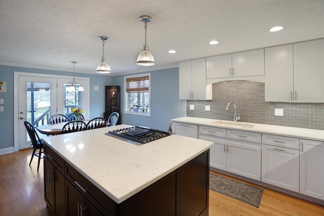 kitchen featuring crown molding, dishwasher, light wood-type flooring, gas cooktop, and a sink