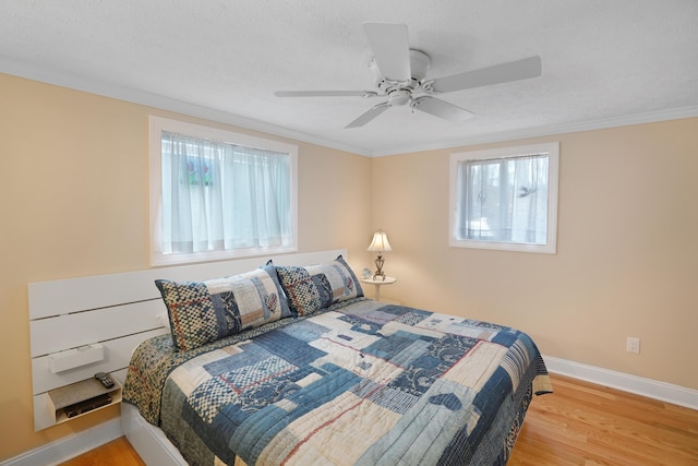 bedroom featuring a textured ceiling, crown molding, baseboards, and wood finished floors