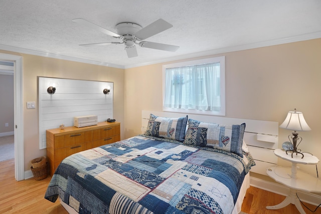 bedroom with light wood-type flooring, a textured ceiling, ornamental molding, and a ceiling fan