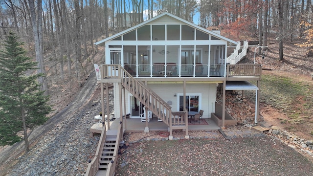 rear view of property with stairs, a deck, and a sunroom