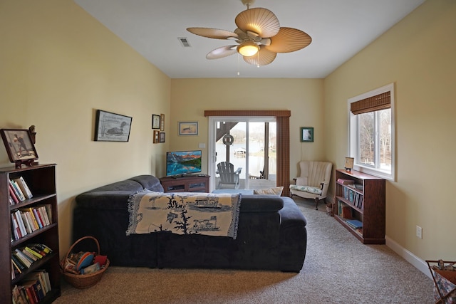 carpeted living area with visible vents, baseboards, and ceiling fan