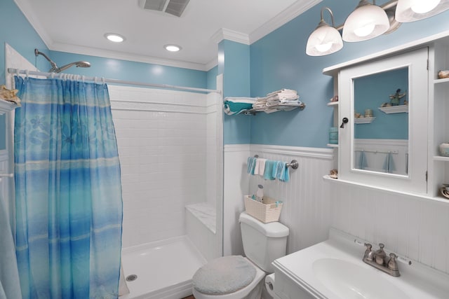 full bathroom featuring a wainscoted wall, visible vents, toilet, a tile shower, and crown molding