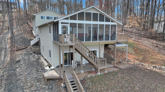 rear view of property featuring stairway, a deck, and a sunroom