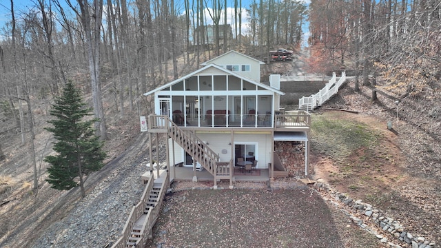 rear view of property featuring stairway, a sunroom, and a wooden deck