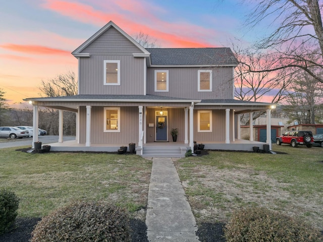 farmhouse inspired home featuring an attached carport, a porch, a front yard, and a shingled roof