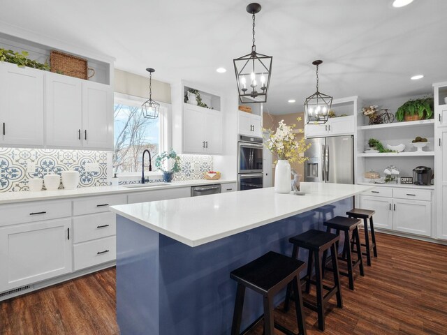 kitchen with visible vents, a sink, a breakfast bar, stainless steel appliances, and open shelves