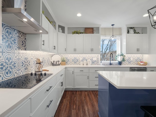 kitchen with light countertops, white cabinetry, wall chimney exhaust hood, black electric cooktop, and a sink