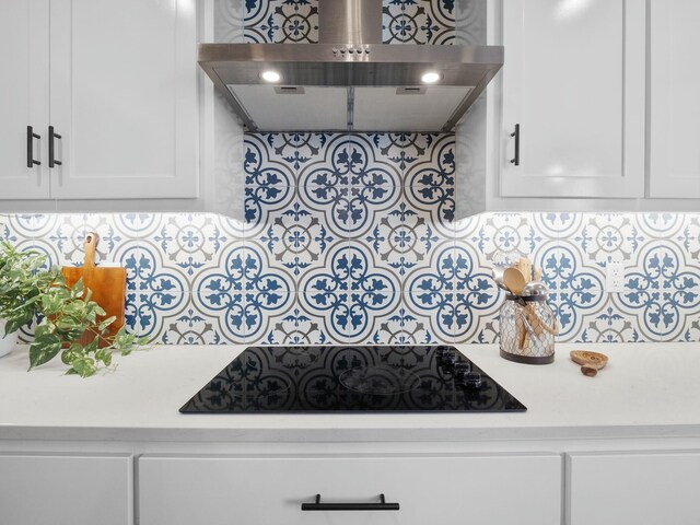 kitchen featuring white cabinets, light countertops, extractor fan, and black electric cooktop