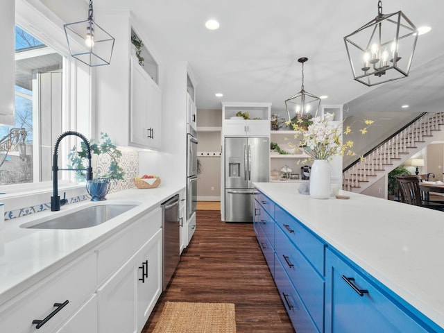 kitchen featuring dark wood finished floors, open shelves, blue cabinetry, a sink, and appliances with stainless steel finishes