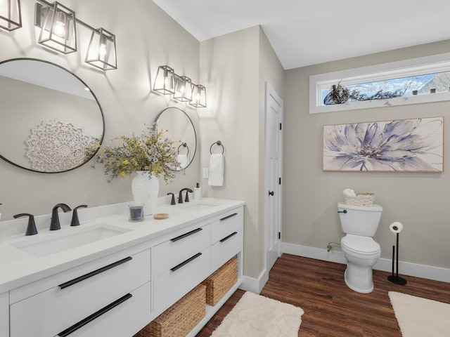 bathroom featuring toilet, wood finished floors, baseboards, and a sink