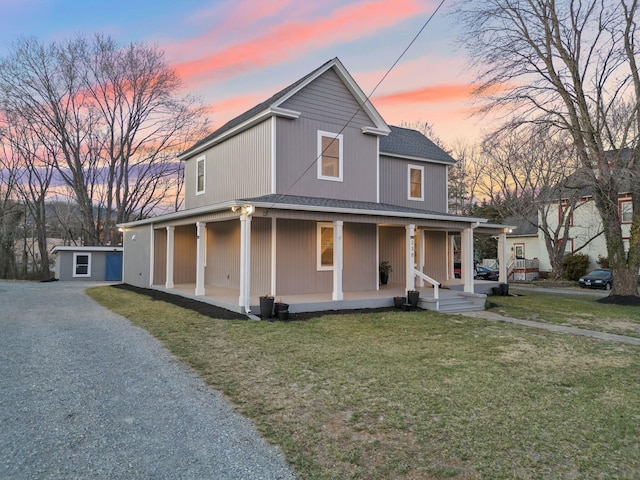 farmhouse featuring covered porch, a lawn, and roof with shingles