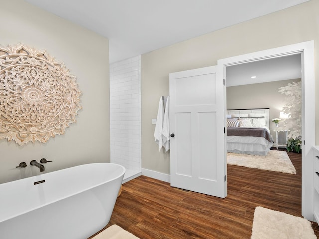 ensuite bathroom featuring a freestanding bath, ensuite bathroom, baseboards, and wood finished floors