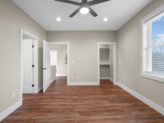 unfurnished bedroom featuring a walk in closet, recessed lighting, baseboards, and dark wood-style flooring