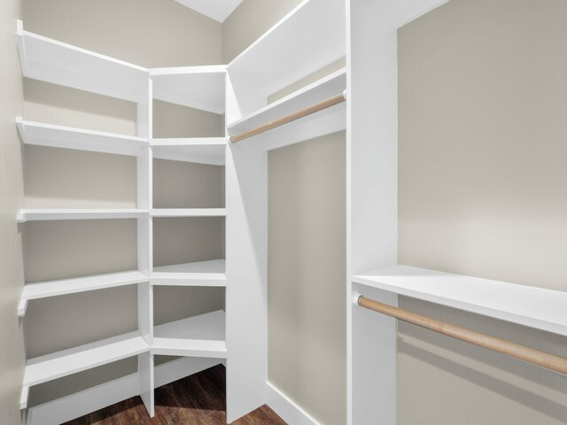 walk in closet with dark wood-style flooring