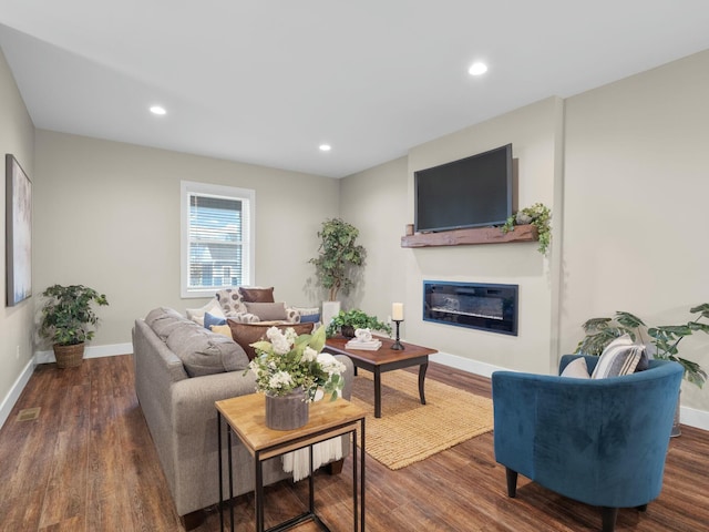 living area with visible vents, a glass covered fireplace, wood finished floors, recessed lighting, and baseboards