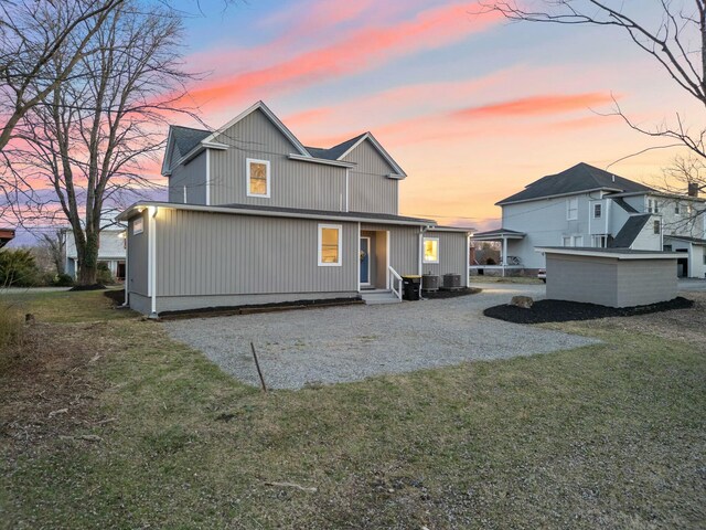 back of house with a lawn, gravel driveway, and entry steps