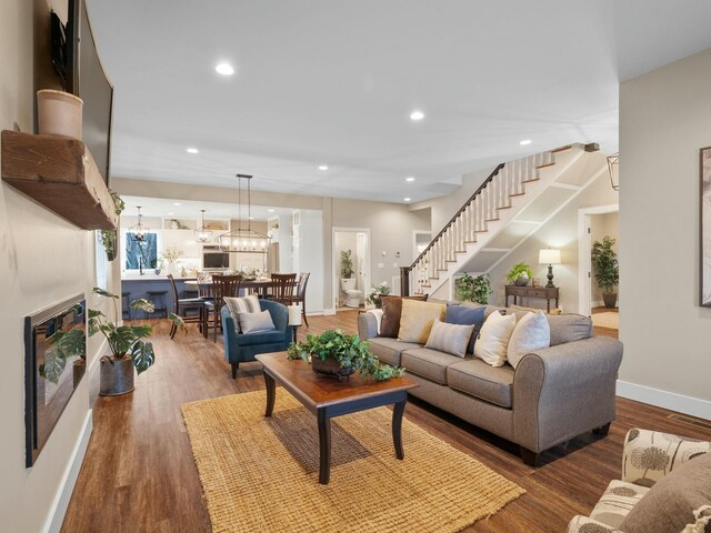 living area featuring wood finished floors, baseboards, recessed lighting, stairs, and a glass covered fireplace