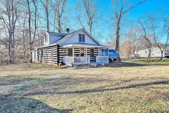 cabin featuring covered porch, log exterior, a chimney, and a front yard