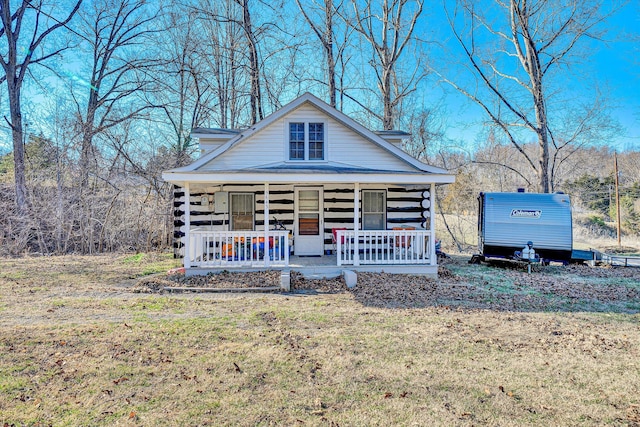 view of front of property with log siding, a porch, and a front lawn