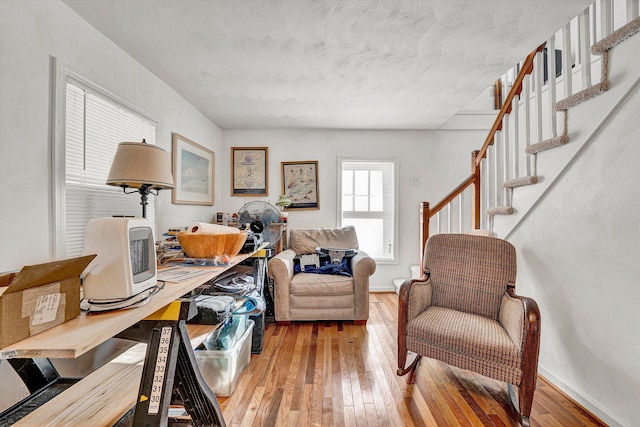 living area with stairs, hardwood / wood-style flooring, and baseboards