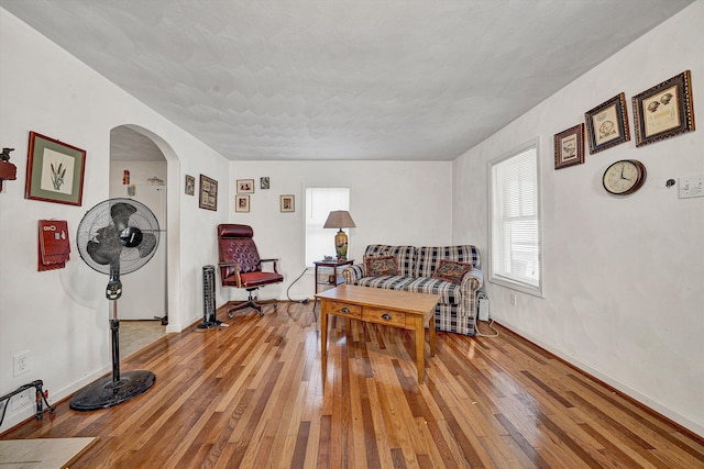 sitting room with baseboards, arched walkways, and hardwood / wood-style flooring