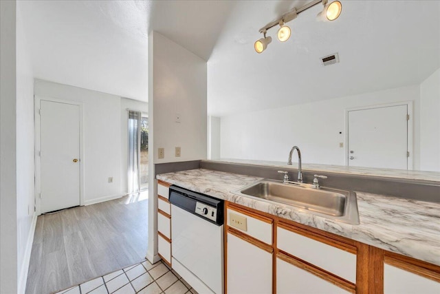 kitchen featuring visible vents, light countertops, lofted ceiling, white dishwasher, and a sink