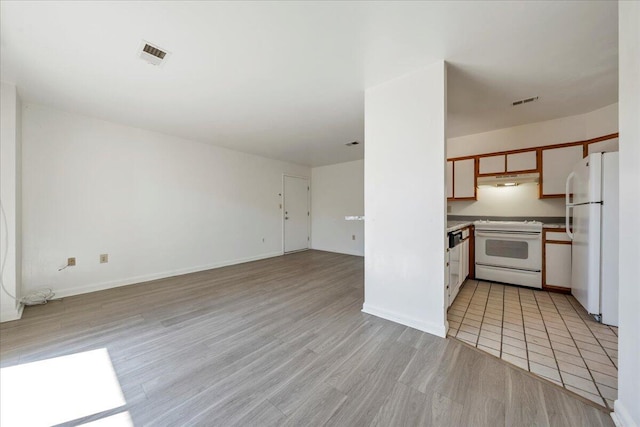 kitchen with under cabinet range hood, white appliances, light wood-type flooring, and light countertops