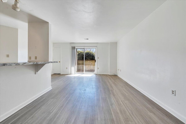 unfurnished living room with baseboards and light wood-style floors