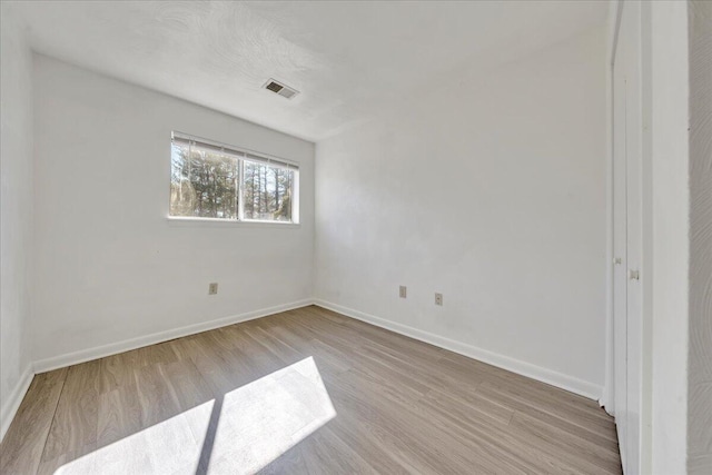 spare room with visible vents, light wood-style floors, and baseboards