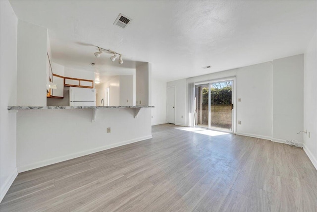 unfurnished living room featuring visible vents, baseboards, and light wood finished floors