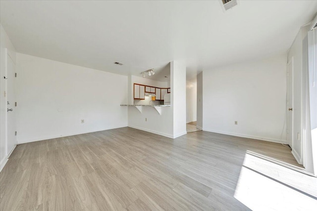 unfurnished living room featuring baseboards, visible vents, and light wood finished floors