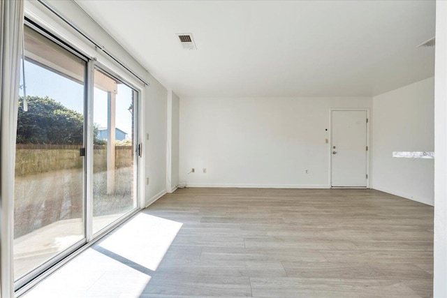 unfurnished room with light wood-style floors, visible vents, and baseboards