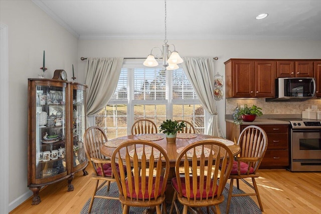 dining space featuring a chandelier, baseboards, light wood-style flooring, and ornamental molding