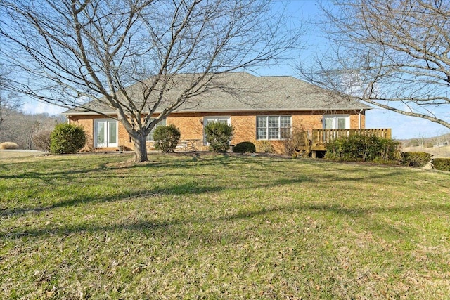 single story home featuring brick siding, a wooden deck, and a front yard