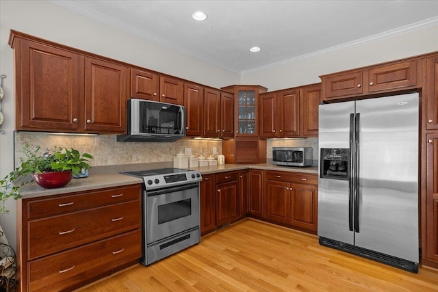 kitchen featuring decorative backsplash, crown molding, light wood-style floors, and appliances with stainless steel finishes