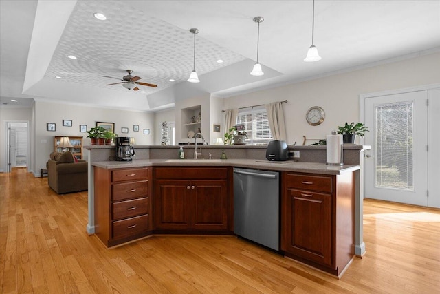 kitchen featuring light wood-type flooring, a sink, a tray ceiling, stainless steel dishwasher, and open floor plan