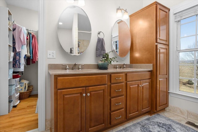 full bath with double vanity, visible vents, baseboards, and a sink