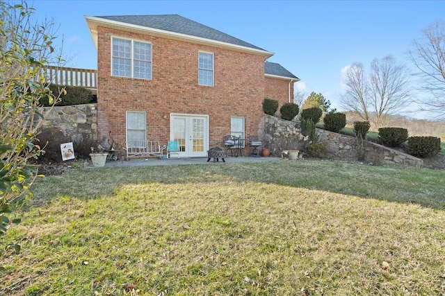 back of house with brick siding, a patio area, french doors, and a yard