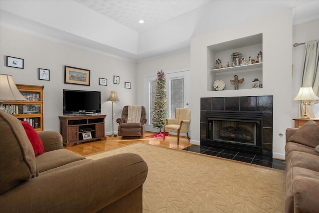 living room with built in shelves, crown molding, baseboards, a fireplace, and wood finished floors