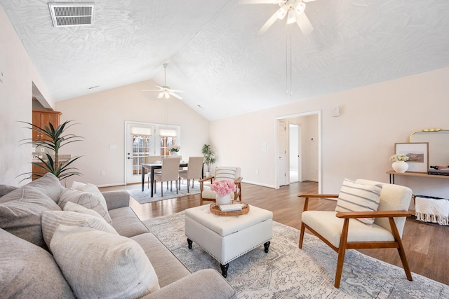 living room featuring visible vents, vaulted ceiling, wood finished floors, a textured ceiling, and a ceiling fan