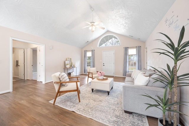 living area featuring vaulted ceiling, baseboards, a ceiling fan, and wood finished floors