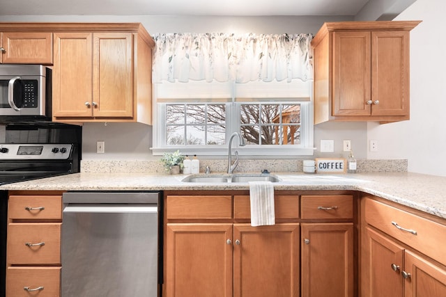 kitchen with a sink, stainless steel appliances, and light stone counters