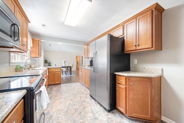 kitchen with a sink, baseboards, brown cabinets, and appliances with stainless steel finishes