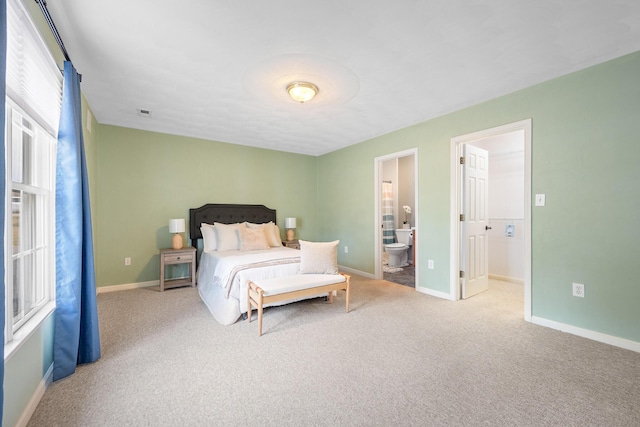 carpeted bedroom with connected bathroom and baseboards