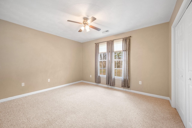 unfurnished bedroom featuring visible vents, baseboards, ceiling fan, a closet, and light colored carpet